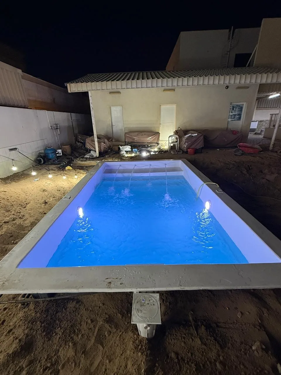 Newly filled pool lit at night with water blades running