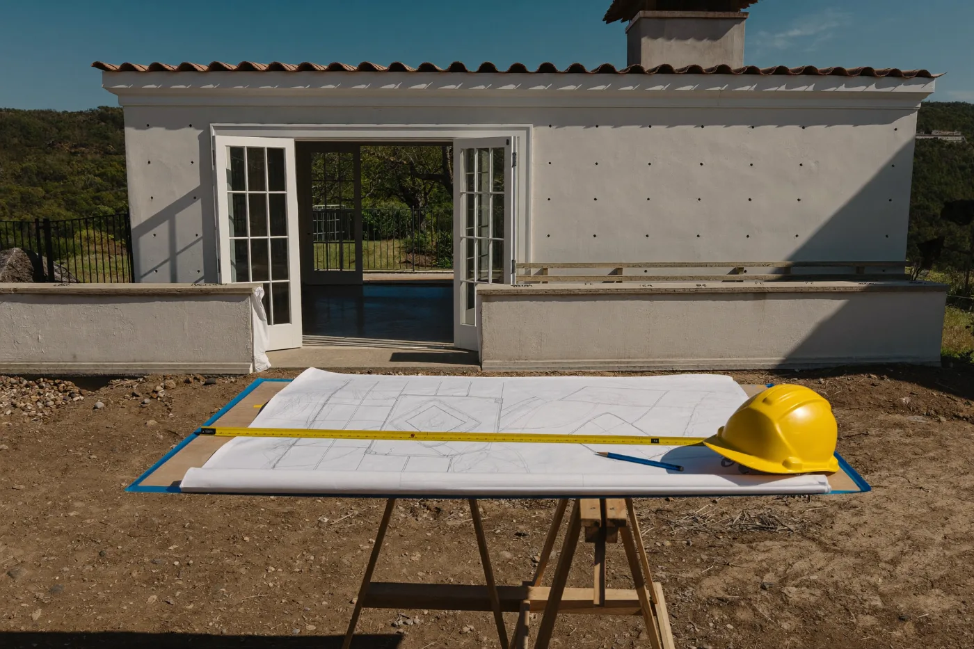 Construction drawings, tape measure and hard hat on a site trestle table