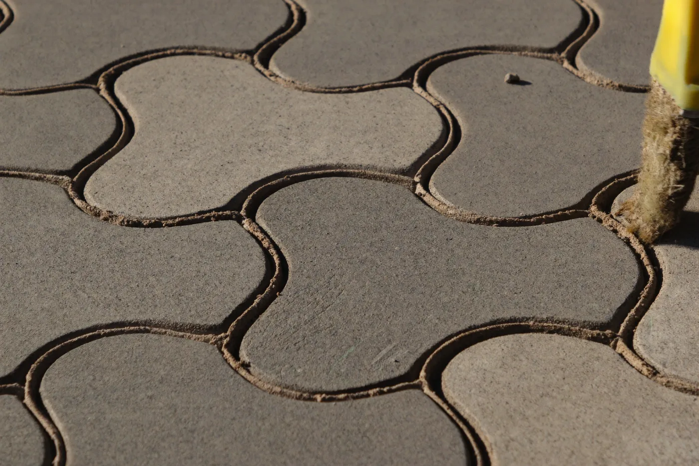 Kiln dried sand being brushed into the joints of herringbone paving