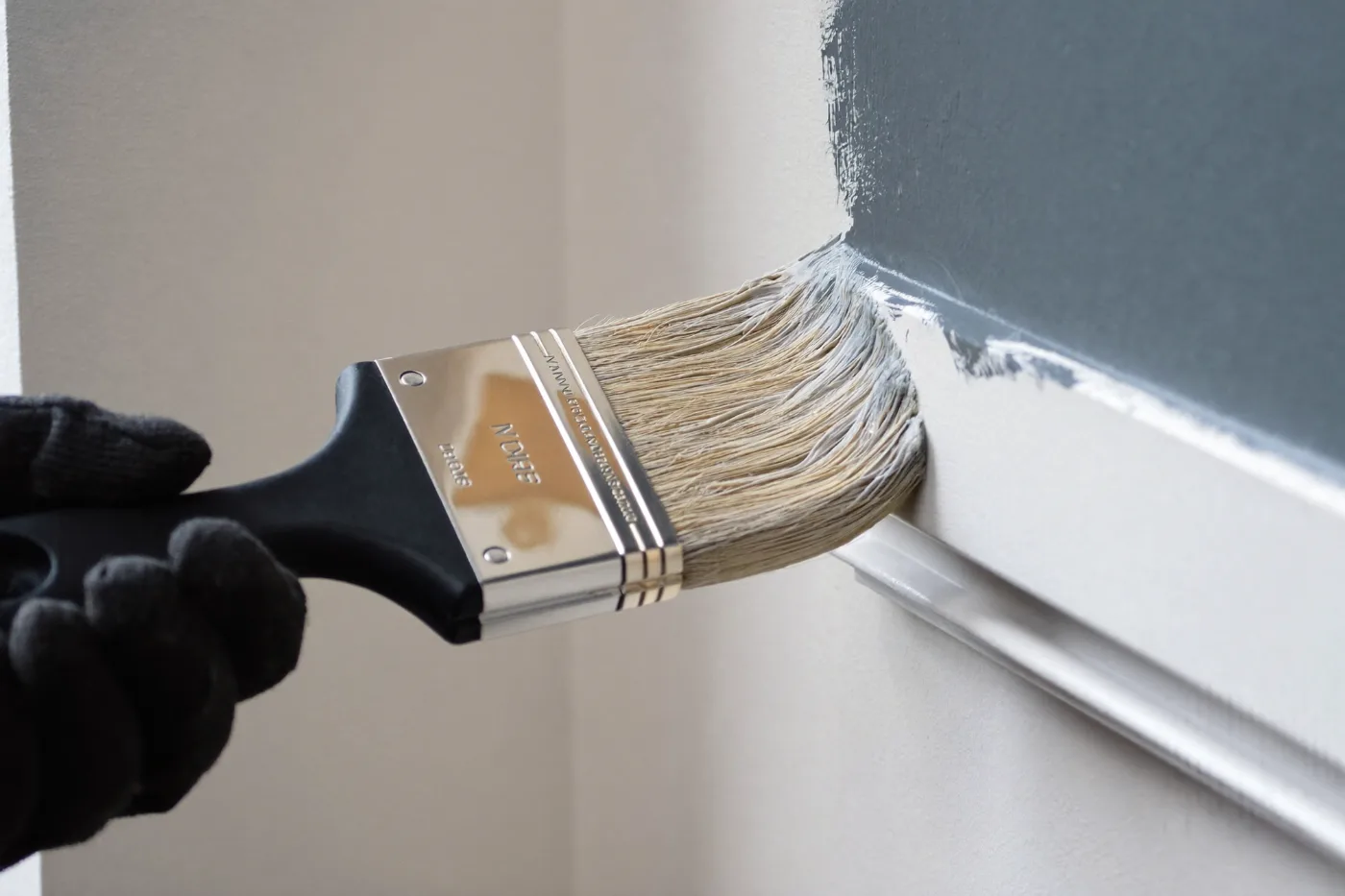Brush cutting a clean line where a painted wall meets white trim