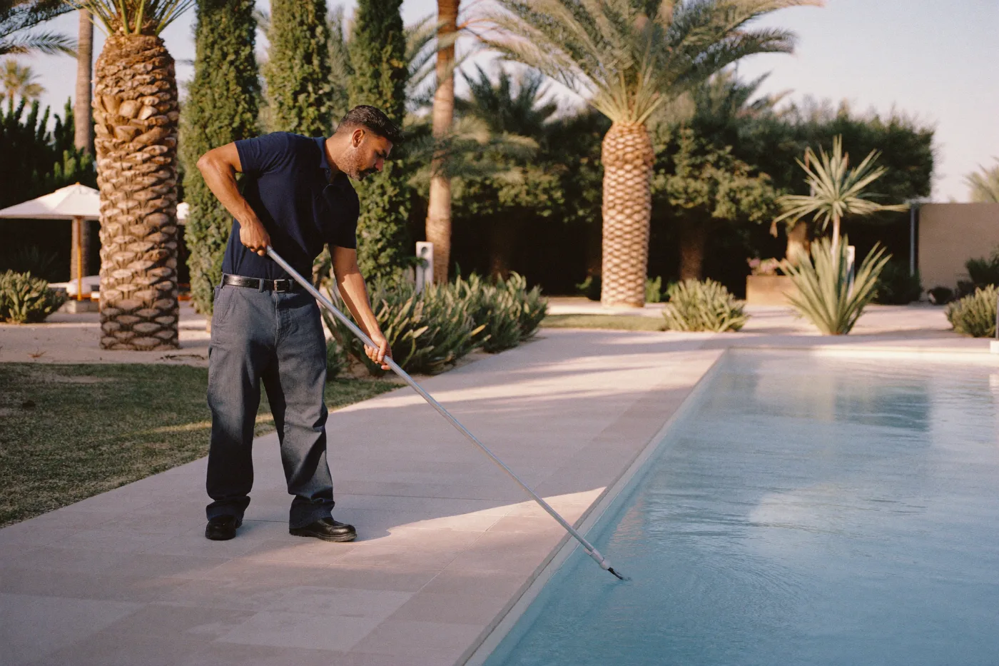 Pool cleaner using a telescopic leaf skimmer across a villa pool