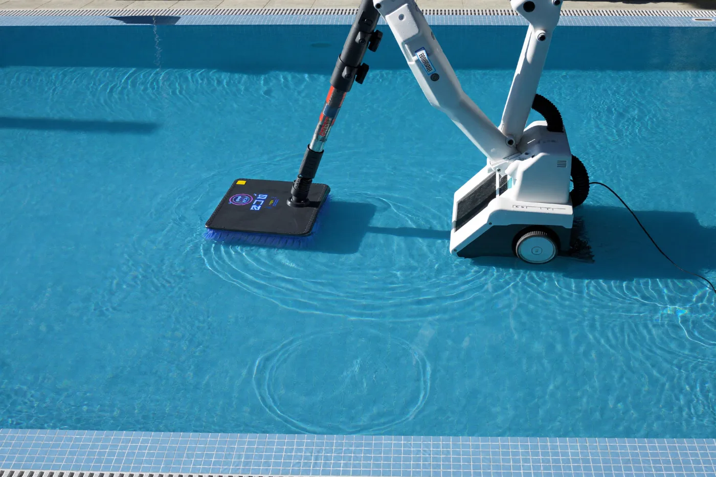 Robotic pool cleaner working across the floor of a clear blue pool