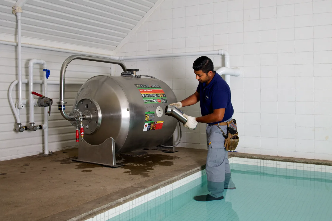 Technician checking the pressure gauge on a pool pump and filter installation