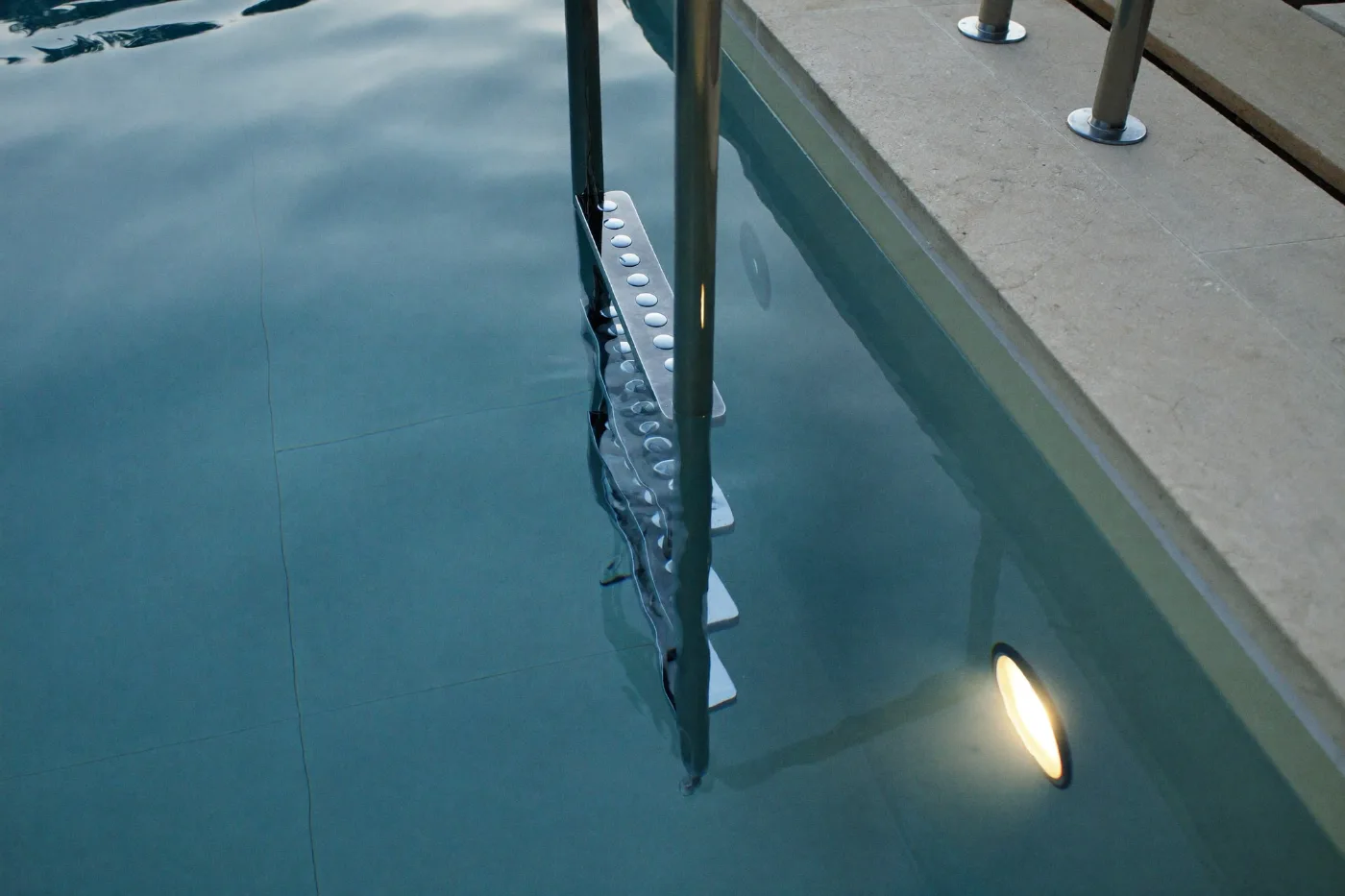 Underwater pool light and stainless steel handrail at a villa pool
